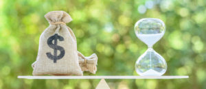 Time value of money, asset growth over time, financial concept : Dollar bags, sand clock or hourglass on a balance scale in equal position, depicts investment in long-term equity for more money growth