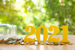 Word 2021 put on coins and glass bottles with coins inside on green bokeh background.Savings New year Concept.