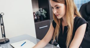 Woman working with documents sitting at desk in office.