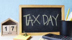 Tax Day concept with wooden calendar 17 May and blackboard