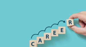 Hand putting wooden cube block on blue background with word CAREER and copy space for your text. Business career planning growth to success concept job change