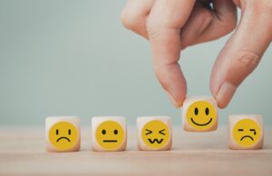 Hand chooses with happy smile face emoticon icons on Wooden Cube , good feedback rating for customer review survey
