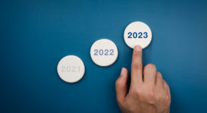 Business growth, profit, and success process concept, year report concept, minimal style. The year 2023 number on white round sponge pointing by hand with moving up arrows on blue background.