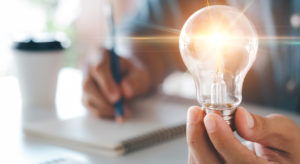 Innovation through ideas and inspiration ideas. Human hand holding light bulb to illuminate, idea of creativity and inspiration concept of sustainable business development.