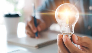Innovation through ideas and inspiration ideas. Human hand holding light bulb to illuminate, idea of creativity and inspiration concept of sustainable business development.