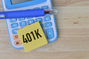 Selective focus of pen, calculator and wooden board written with 401k. A business concept.