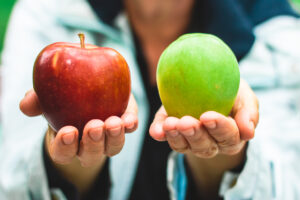 Senior woman holding a red and green apple in each hand – Giving healthy and delicious snacks - Alternative, low calories vegetarian diet