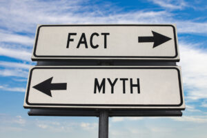 Fact versus myth road sign with two arrows on blue sky background. White two street sign with arrows on metal pole. Two way road sign with text.