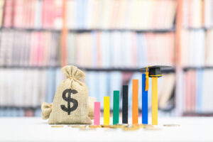 Tuition payment or tuition fee or expense for graduate study abroad program concept : Black graduation cap on wood bar graph, depicts fees charged by education institution for instruction or services.