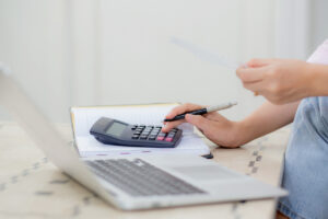 Closeup hands of woman calculating finance household with calculator on desk at home, girl checking bill for saving and planning expenses, debt and loan, tax and accounting, business and financial.