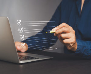 Quality control assurance of the ISO concept. A businessman in a navy blue shirt using an electronic pen to tick the correct sign mark in an online document checklist while sitting at the desk